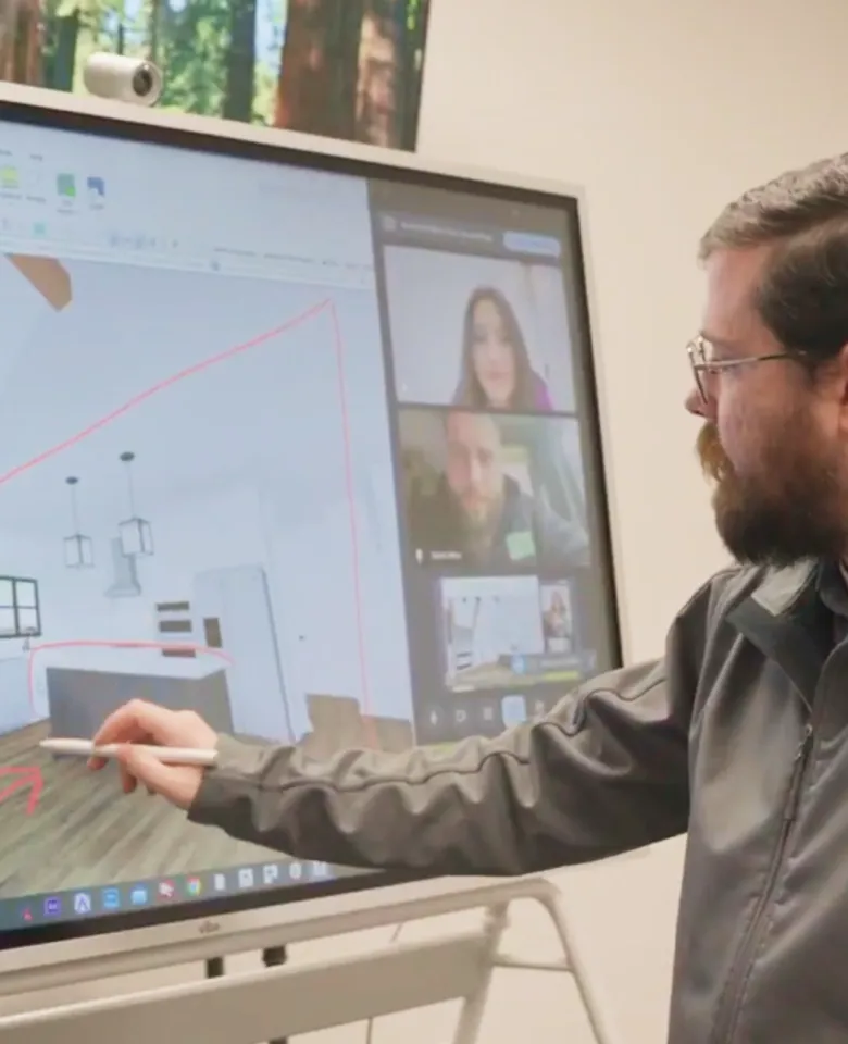 A man using a stylus on a Vibe Board showing a 3D kitchen design and a video call.