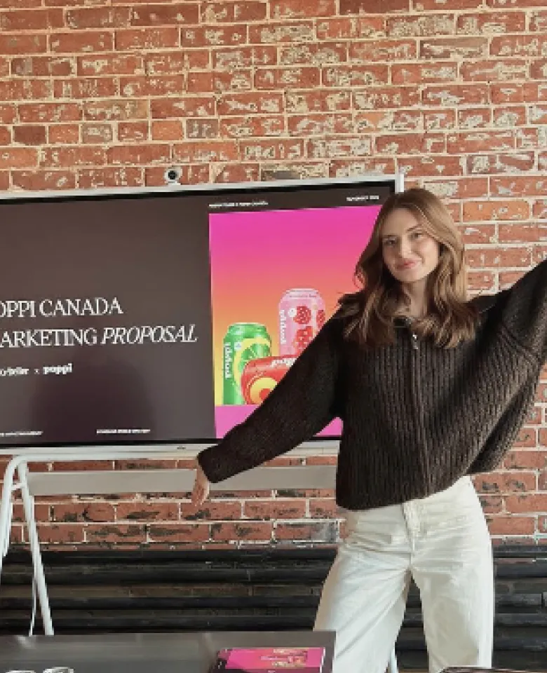 A woman presenting a marketing proposal on a Vibe Board in front of a brick wall.