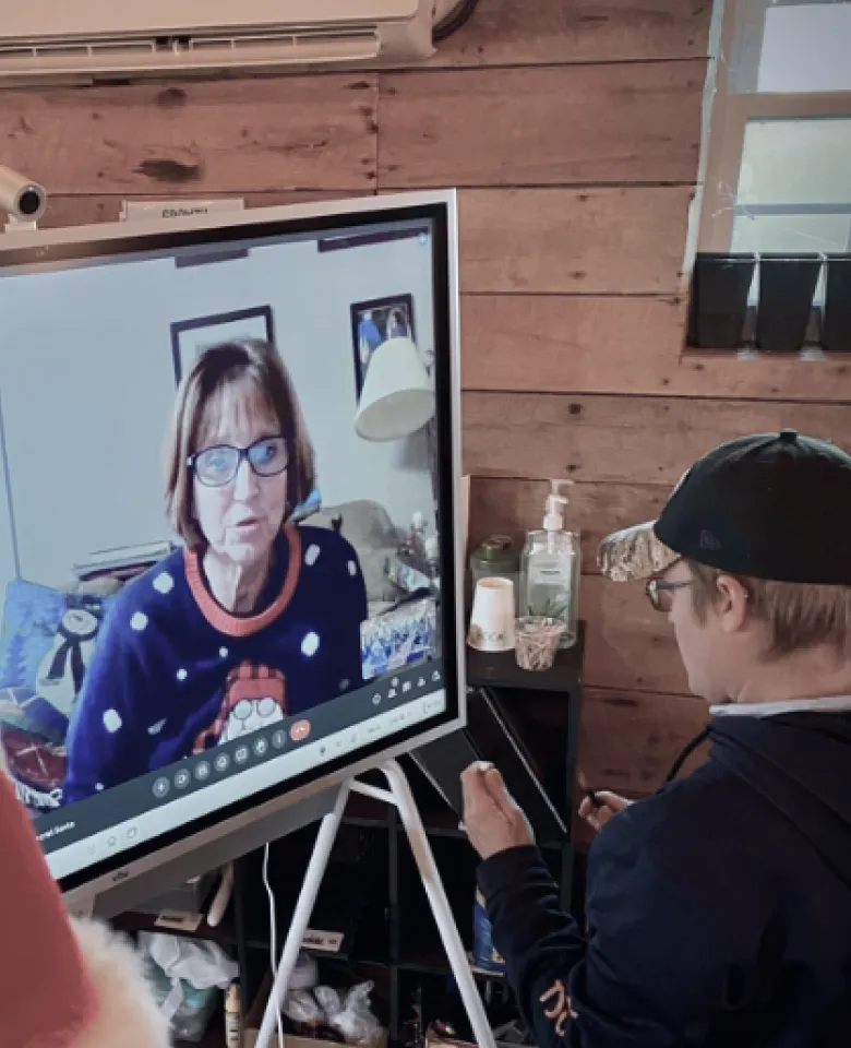 A person wearing a baseball cap looking at a video call on a Vibe Board.