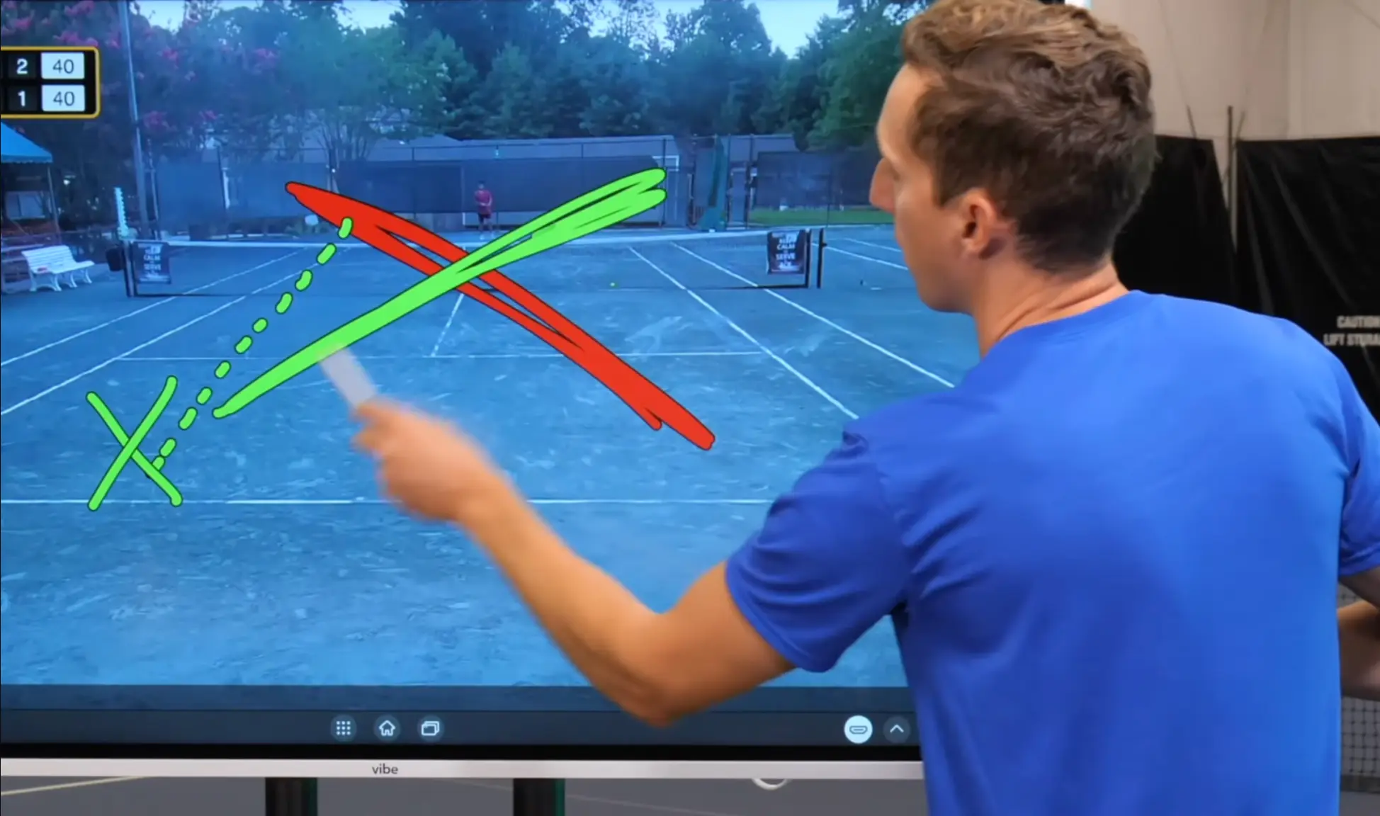 Tennis coach drawing play diagrams on a Vibe Board with a stylus, displaying court footage with annotation overlay