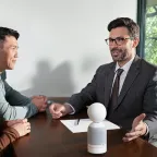 Vibe Dot on conference table capturing live transcript of business meeting discussion between three people